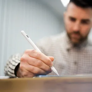 Skriva aktiv stylus för iPad i vitt, visad vid handskrift på en surfplatta med USB-C-laddningsport synlig